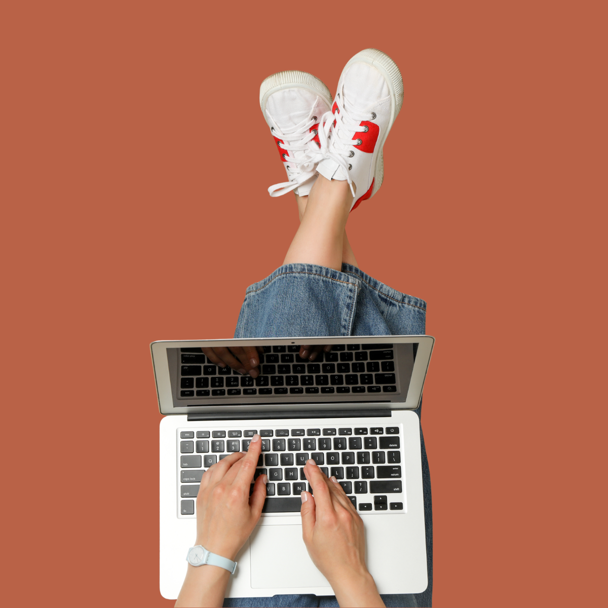 Overhead view of a person typing on a laptop with feet up