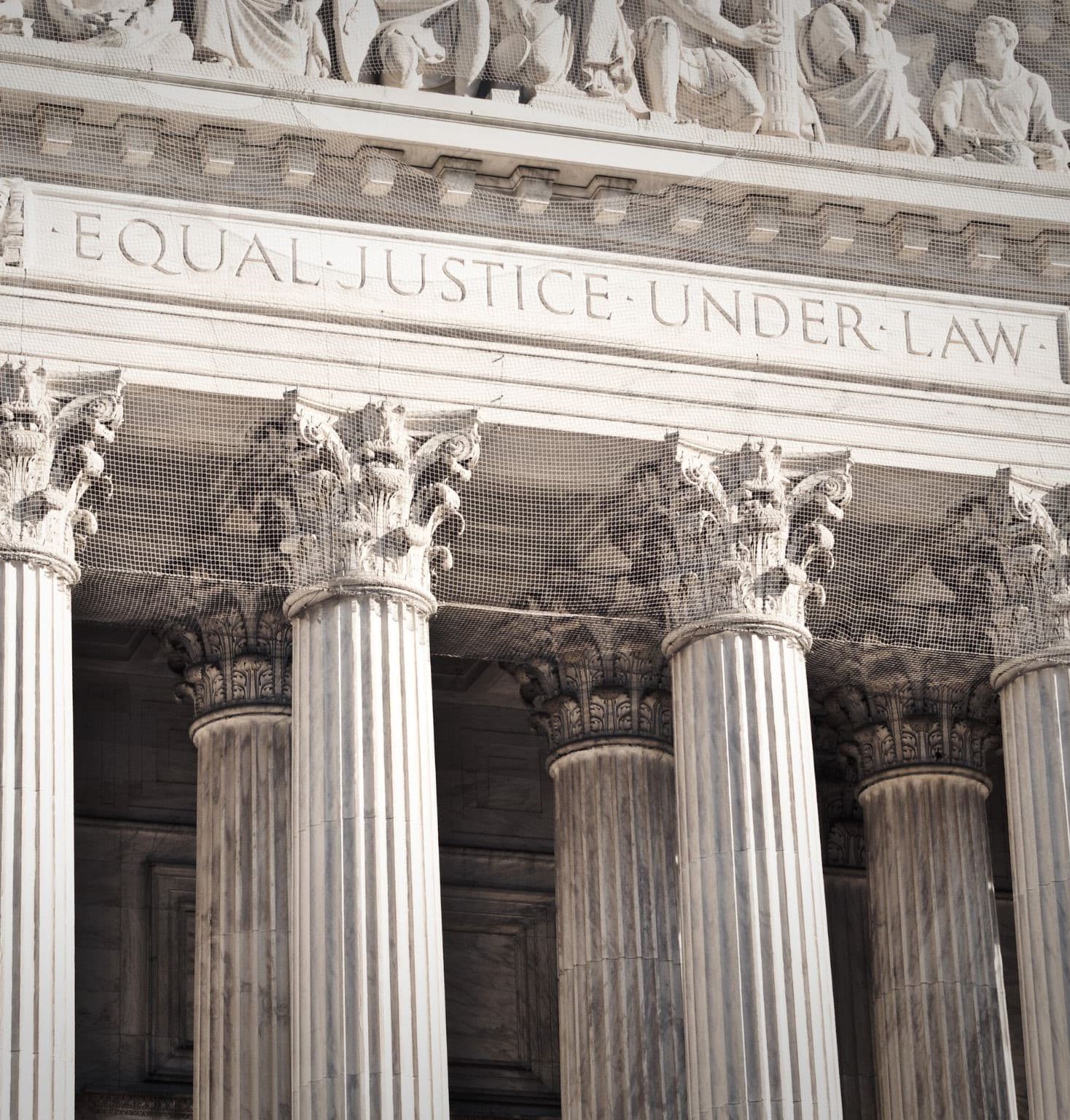 The words EQUAL JUSTICE UNDER LAW carved into the stone facade above the columns of a courthouse
