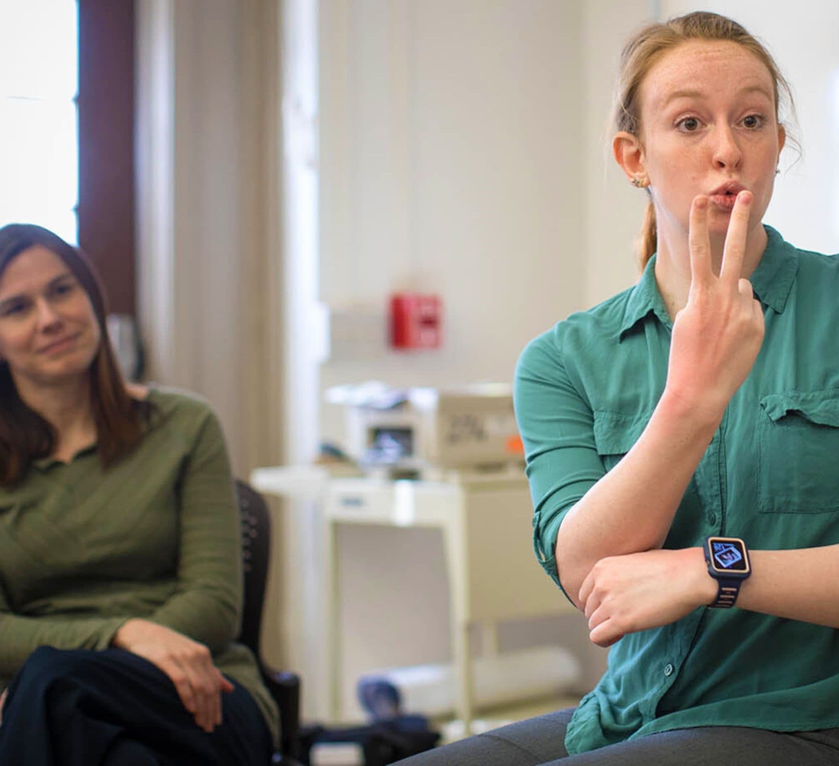 An interpreter signs to a client during a counseling session in a small office