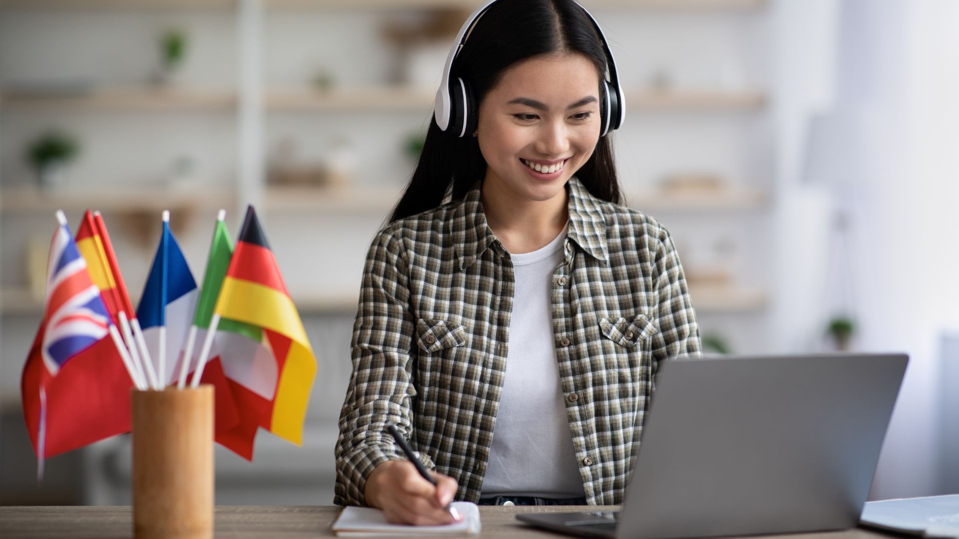 Translator working at a laptop with international flags nearby