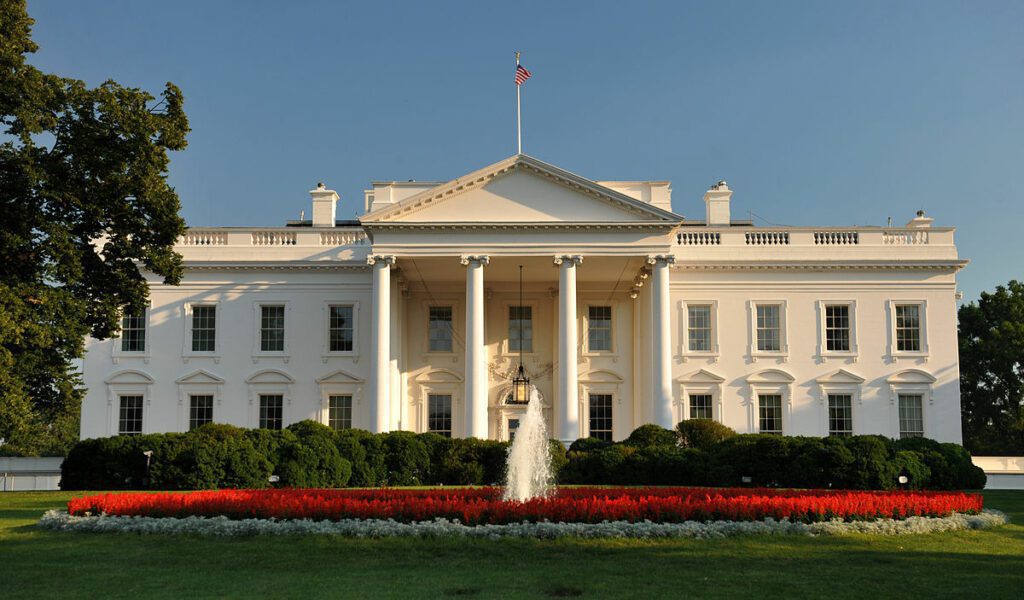 The White House in Washington, DC, seen across its lawn on a clear day.