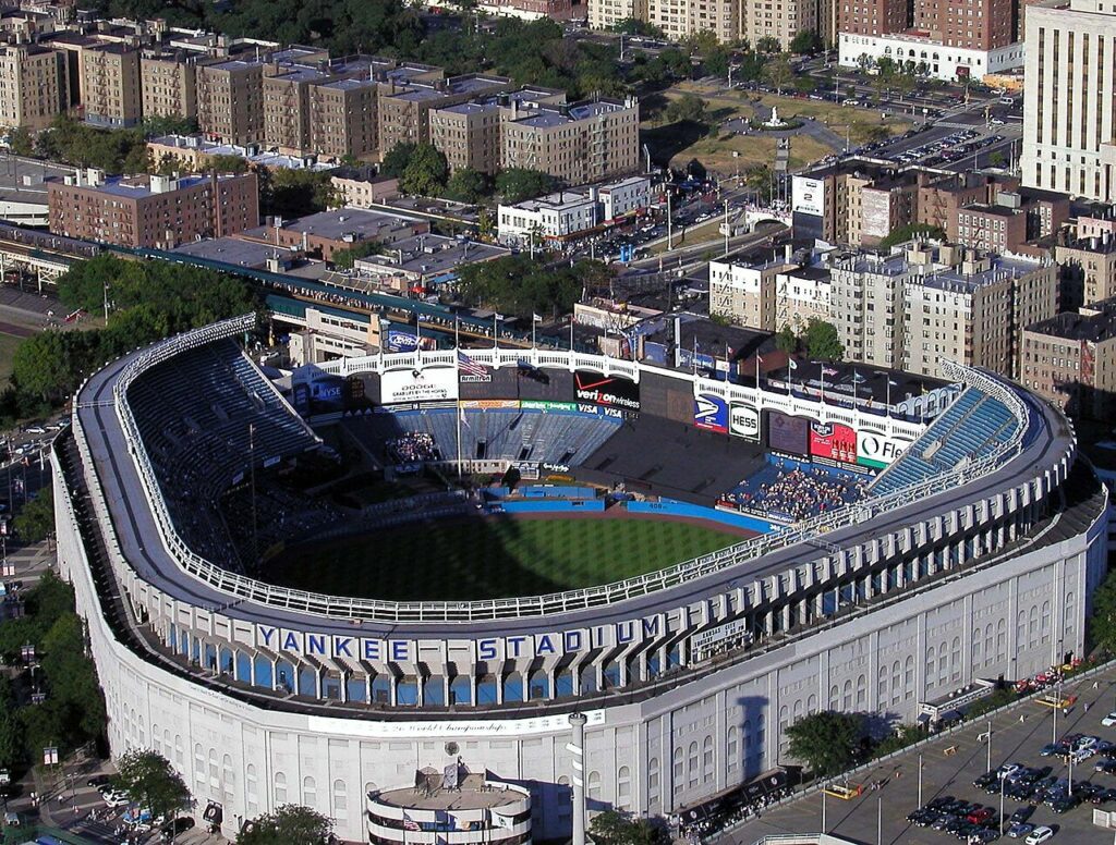 Yankee Stadium seen from the stands, the infield and outfield below a full lower bowl on a bright afternoon.